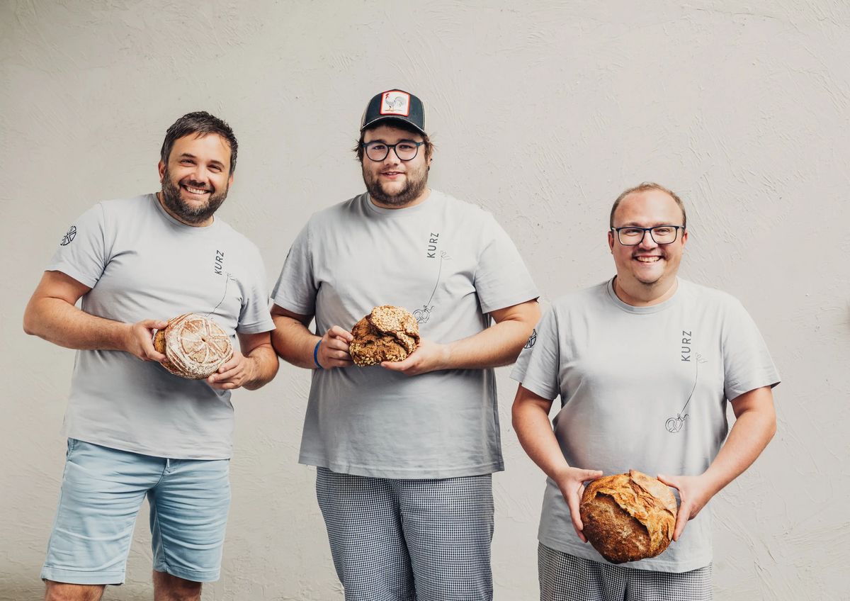 Hannes Kurz, Julian Kurz und Backstubenleiter Mario halten jeweils einen Laib Brot in die Kamera.