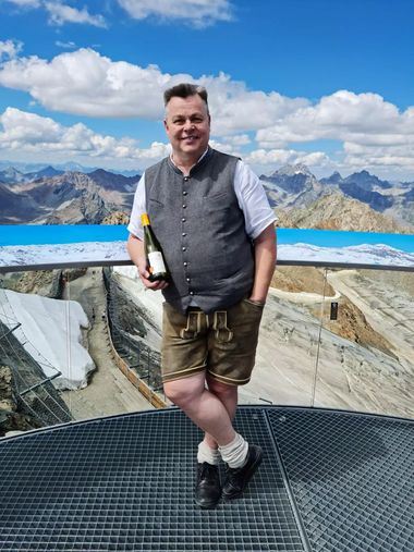 Portrait von Christoph Hauser mit einer Weinflasche